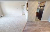 Located at 145 Essex Rd in Warwick, Rhode Island, this 720-square-foot, single-floor apartment offers a practical and well-organized layout comprising one bedroom, one bathroom, a combined kitchen and living area, and a dedicated closet. The open kitchen is equipped with warm-toned wood cabinetry, granite countertops, a stainless steel sink, a black gas range with overhead exhaust hood, a dishwasher, and a full-size refrigerator — providing ample functionality for everyday cooking. A half-wall divider separates the kitchen from the adjoining living area, which features neutral-toned carpet flooring, baseboard heating, and a wall-mounted air conditioning unit. Large windows with vertical blinds allow natural light to fill both the living room and the 200-square-foot bedroom, which also features carpet flooring and baseboard heating. The bedroom is accompanied by a dedicated closet with built-in shelving on both sides, offering practical storage. The bathroom includes a full-size soaking tub and shower combination with chrome fixtures and clean white surround. Neutral wall tones and carpet flooring throughout lend the unit a cohesive, understated aesthetic.