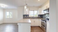 Located on K.L.O. Road in Kelowna, BC, this two-storey home offers a clean, modern design spread across two functional floors. The main floor hosts the open-concept kitchen and living area, finished with warm hardwood-style flooring throughout. The kitchen is a standout feature, showcasing crisp white cabinetry, stone-look countertops, a central island with pendant lighting, a grey subway tile backsplash, and stainless steel appliances. A window above the sink frames scenic mountain views, filling the space with natural light and a connection to the surrounding Okanagan landscape. The living area flows seamlessly from the kitchen, creating an inviting, communal atmosphere. A dedicated laundry room on the main level includes a full-size washer and dryer with overhead shelving for added convenience. Upstairs, three bedrooms offer comfortable retreats, with the primary bedroom featuring mirrored sliding closet doors and built-in shelving. Additional bedrooms are finished with plush carpeting and bright windows. Two full bathrooms, each with a soaker tub and shower surround, serve the home. A hallway and two staircases connect the floors, ensuring a practical and well-organized layout throughout.