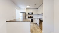 Located in Phoenix, AZ, this single-story, 3-bedroom, 2-bathroom home offers a clean, modern aesthetic with light wood-style flooring that flows consistently throughout every room. The kitchen is a standout feature, showcasing sleek white cabinetry extending to the ceiling, a white subway tile backsplash, a peninsula with a dark countertop ideal for casual dining or meal prep, and a full suite of stainless steel appliances including a gas range, microwave, refrigerator, and dishwasher. The living room is bright and airy, featuring a ceiling fan and vertical blinds that allow for natural light control. The primary bedroom is generously sized with its own closet, while the two additional bedrooms offer versatile space along the same light-floored corridor. The hallway connects the living areas to the bedrooms with efficient flow. Both bathrooms are finished in a consistent neutral palette with wood-look tile flooring, a vanity with dark countertop accents, and walk-in shower with grab bars. A dedicated laundry area with a full-size washer and dryer is accessible from the exterior, providing practical utility. The home's crisp white walls and cohesive finishes create a bright, move-in-ready atmosphere throughout.