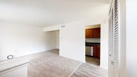 This two-floor residence offers a clean, functional layout designed for comfortable everyday living. The main living area is finished with neutral wall-to-wall carpeting and opens directly to a separate kitchen, creating a natural flow between spaces. The kitchen is well-appointed with warm-toned wood cabinetry, dark granite-style countertops, and stainless steel appliances including a gas range, dishwasher, and refrigerator, all set over wood-look flooring that adds a durable, practical touch.

A central staircase with a white-painted banister connects the two floors, with a built-in closet and entry-way storage nearby, adding to the home's organizational appeal. The upper level features additional carpeted living space bathed in natural light from a window fitted with vertical blinds, along with access to the kitchen and a closet-lined hallway. The bedrooms are generously proportioned, each carpeted and bright, with windows that invite in natural light.

The bathroom is neatly finished with a wood-toned vanity, granite-style countertop, a large mirror with overhead lighting, and a full tub-shower combination. Throughout the home, white walls and consistent finishes create a cohesive, move-in ready environment.