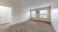Located at 1420 Pennsylvania Ave in Des Moines, Iowa, this one-bedroom, one-bathroom unit offers a practical and comfortable single-floor layout. The living room is generously sized, featuring neutral-toned carpet, a textured ceiling, dual windows that invite natural light and neighborhood views, a wall-mounted air conditioning unit, and baseboard heating for year-round climate control. The open flow from the living room leads through a hallway into the rest of the unit. The bedroom is a well-proportioned room with plush carpeting, a ceiling fan with integrated light fixture, a window overlooking the outdoors, and baseboard heating. It connects to closet space that features built-in shelving rods and wood-look vinyl flooring. Three closets total are distributed throughout the unit, providing ample storage. The bathroom is equipped with a full tub-and-shower combination featuring white tile surround, tile flooring, and standard fixtures. The kitchen completes the layout, offering functional space for everyday cooking. Neutral cream-toned walls are consistent throughout, creating a clean and cohesive look. The unit also includes a hallway that efficiently connects the main living areas. Baseboard heating is present in multiple rooms, ensuring warmth across the entire space.