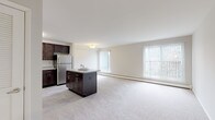 Located at 300 E Marshall St in Pennsylvania, this single-floor residence offers a well-designed, functional layout that balances comfort and practicality. The open-concept living and kitchen area serves as the heart of the home, where a generously sized living space flows seamlessly into a fully equipped kitchen. The kitchen is outfitted with rich, dark-stained cabinetry offering ample storage, granite-style countertops, a central island, and a full suite of stainless steel appliances including a refrigerator, electric range, microwave, and dishwasher. Light tile flooring in the kitchen complements the neutral tones throughout the space. Large windows in the living area admit abundant natural light and frame views of surrounding greenery, creating a bright and airy atmosphere. The bedrooms are carpeted and generously proportioned, each featuring baseboard heating and access to natural light. The bathrooms are clean and functional, featuring white vanities with under-sink storage, mirrored medicine cabinets, and tiled floors. One bathroom includes a shower-tub combination. Soft, neutral wall tones and plush carpeting throughout the living and sleeping areas contribute to a calm, welcoming ambiance. The overall layout, as seen in the dollhouse view, provides a practical flow between all areas of the home.