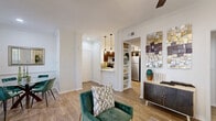 Located at 2400 Spring Rain Dr in Spring, TX, this well-appointed one-bedroom, one-bathroom residence offers a smart, functional layout across a single floor. Wood-look flooring flows throughout, providing a cohesive and warm aesthetic. The open-concept living and dining area is bright and inviting, featuring crown molding, a ceiling fan, and a window that brings in natural light. The kitchen is a standout feature, equipped with rich dark-wood cabinetry, white quartz countertops, a subway tile backsplash, and a full suite of stainless steel appliances including a refrigerator, range, and dishwasher. A peninsula with pendant lighting connects the kitchen to the dining area, enhancing the open feel. The bedroom offers a comfortable retreat with a ceiling fan, a natural light-filled window, a built-in desk nook with open shelving, and ample closet space. The bathroom includes a full tub-shower combination with marble-style tile surround. A dedicated laundry area with side-by-side washer and dryer hookups adds everyday convenience. Additional storage is provided through multiple closets and a pantry, making this residence as practical as it is stylish.