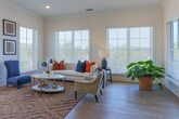 Located at 1180 Canton St in Roswell, GA, this single-floor residence presents a thoughtfully designed open-concept layout finished in a clean, neutral palette. The living room is a standout space, wrapped in large windows with plantation shutters that invite abundant natural light and offer outdoor views. Light hardwood flooring flows throughout the main living areas, complementing the airy, modern atmosphere.

The kitchen is well-appointed with gray shaker-style cabinetry stacked to the ceiling, white quartz countertops, stainless steel appliances including a gas range and French door refrigerator, and a central island with seating — all illuminated by pendant lighting. An adjacent dining area provides a natural gathering space with additional natural light.

The bedrooms are carpeted and generously proportioned, with ceiling fans and large windows. Walk-in closet space is available, adding to the functional storage of the residence. The primary bathroom features slate-blue cabinetry, a sleek vanity with modern fixtures, tile flooring, and a glass-enclosed walk-in shower. A secondary full bathroom includes subway tile surround with a combination tub and shower.

Throughout, the home maintains a cohesive, contemporary design with recessed lighting, crown molding details, and a bright, welcoming ambiance.