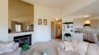 This single-floor residence at 1015 East Cozza Drive, Unit 48 in Spokane, Washington offers a well-organized and comfortable layout with a warm, neutral palette throughout. The living room serves as the heart of the home, highlighted by a tile-surround fireplace with brass accents and vaulted ceiling detail that adds visual depth. Large windows flood the space with natural light while offering pleasant views of the surrounding greenery. Built-in shelving provides both functional storage and display space, enhancing the room's character. The kitchen features light wood cabinetry, ample counter space, and a seamless connection to the dining area, which opens to a private balcony through a sliding glass door — an ideal spot for enjoying outdoor views. The bedrooms are carpeted and generously sized, each offering closet storage and windows that bring in natural light. One bedroom includes direct access to a bathroom, adding convenience and privacy. The bathroom is clean and functional, featuring a wide vanity with a large mirror and wood-tone cabinetry. A carpeted hallway with flush ceiling lighting connects the rooms efficiently. Throughout the space, soft tones and textured ceilings contribute to a cohesive, understated aesthetic suited for comfortable everyday living.