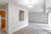 This single-floor residence offers a practical and straightforward layout designed for comfortable everyday living. The spacious living room is finished with neutral-toned carpet and features large sliding glass doors that invite natural light and provide direct access to an outdoor patio area with greenery views. A distinctive louvered pass-through window connects the living area to the kitchen, enhancing the sense of openness between the two spaces.

The kitchen is equipped with warm oak cabinetry — both upper and lower — offering ample storage, complemented by dark-speckled laminate countertops, a stainless steel sink, and a gas range with overhead ventilation. The tile flooring in the kitchen provides a practical contrast to the carpeted living areas.

The bedrooms are generously sized, each featuring neutral carpet, bright windows with outdoor views of surrounding trees and landscaping, and built-in closets with sliding or hinged doors providing solid storage. One bedroom benefits from a large window framing a pleasant wooded view.

The bathroom is functional and well-appointed, featuring a warm wood-toned vanity with a white basin sink, a mirrored medicine cabinet with overhead lighting, white tile wainscoting, and tile flooring, contributing to a clean, utilitarian aesthetic throughout.