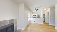 This efficiently designed single-floor residence offers a thoughtful layout across its one bedroom and one bathroom. The open-concept living area is anchored by a striking tile-surround fireplace and features light hardwood flooring that extends throughout the main living spaces. Vaulted ceilings in the living area lend a sense of spaciousness, complemented by a ceiling fan. A sliding glass door opens to a private patio, inviting abundant natural light and outdoor views of surrounding greenery.

The kitchen is well-appointed with white cabinetry, a classic subway tile backsplash, dark countertops, and a full suite of stainless steel appliances including a refrigerator, range, microwave, and dishwasher. A breakfast bar peninsula connects the kitchen to the living area, creating a functional and social flow. Multiple windows fitted with horizontal blinds provide natural light throughout.

The bedroom offers plush carpeting, a bright window with outdoor views, and convenient access to a dedicated closet. The bathroom includes white cabinetry, warm countertops, and a tub-shower combination with tiled surround. Clean, neutral tones throughout the space create a calm and cohesive ambiance.