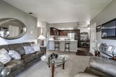 Located at 13151 Yorba Ave in Chino, CA, this single-story home offers a comfortable and functional layout with thoughtfully designed living spaces throughout. The living room is carpeted and generously sized, featuring a sliding glass door that opens to a private balcony, allowing natural light to fill the space. A wall-mounted flat-screen TV and decorative accents complete the inviting atmosphere.

The kitchen is a standout feature, outfitted with rich dark wood cabinetry, white countertops, stainless steel appliances including a gas range, microwave, dishwasher, and refrigerator, along with recessed lighting and a tray ceiling detail. Wood-look flooring adds warmth to the space. Adjacent to the kitchen, the dining area provides an intimate setting with a round glass-top table.

The primary bedroom offers carpeted floors, a mirrored sliding closet, and tasteful décor. Additional bedrooms provide flexible living options with ample natural light and carpeted floors. Both bathrooms feature wood-look flooring, tub-shower combinations, dark wood vanities, and white countertops. A hallway connects the main living areas to the private bedrooms, creating a well-organized and easy-to-navigate floor plan throughout this welcoming home.