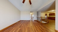 Located at 5510 Dodge Ct in Wichita, Kansas, this two-story home offers generous living space spread across two floors, plus a basement. The main level features a combined kitchen and living room with warm hardwood-style laminate flooring, vaulted ceilings accented by a ceiling fan, and a wood-railed staircase. The kitchen is equipped with medium-toned wood cabinetry, a double sink, granite-style countertops, and a dishwasher, with a dedicated laundry room just steps away housing a full washer and dryer set beneath overhead cabinetry. The upper level hosts the primary bedroom, a well-sized retreat with plush carpeting and a ceiling fan, with direct access to the shared bathroom. The bathroom features a dual-sink vanity with rich wood cabinetry, granite-style countertops, and tile flooring. Three additional bedrooms are carpeted and finished with consistent warm-toned baseboards and trim throughout. The basement is partially framed with drywall in progress, offering a blank canvas for future living space or storage. This home presents a functional, practical layout with consistent finishes and a neutral color palette suited for a variety of lifestyles.