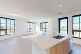Located at 1901 29th St in Denver's vibrant River North Art District, this well-appointed two-bedroom, two-bathroom residence offers a thoughtfully designed open-concept floor plan with modern finishes throughout. The living and dining areas flow seamlessly into the kitchen, all anchored by large black-framed grid windows that bathe the space in abundant natural light and frame panoramic views of the Denver cityscape.

The contemporary kitchen features warm wood cabinetry, a white quartz waterfall island with an undermount sink, a subway tile backsplash, and a full suite of stainless steel appliances. Light wood-tone luxury flooring runs throughout the main living areas, enhancing the bright, airy aesthetic.

Both bedrooms are well-proportioned and carpeted for comfort, each equipped with ceiling fans and large black-framed windows that continue the city view theme. Each bedroom is served by its own closet, and the primary bedroom offers access to a dedicated bathroom. The second full bathroom includes a wood-vanity with a white countertop, a large mirror, and a tub-shower combination with clean white tile surround.

A clean, well-lit hallway with recessed lighting connects the bedrooms, closets, and bathrooms, completing this cohesive and modern residence ideal for urban living in Denver.