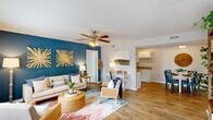 Located at 137 Dapple Ct in Wilmington, NC, this single-story 2-bedroom, 2-bathroom home offers a well-designed layout across a comfortable footprint. The open living and dining area serves as the heart of the home, featuring wood-style flooring, a textured ceiling, and a ceiling fan overhead. A bold teal accent wall adds a pop of coastal character to the living room, which receives natural light through well-placed windows. The adjacent dining area provides an intimate space for meals. The galley-style kitchen is outfitted with white cabinetry, granite-look countertops, black appliances including a refrigerator, range, microwave, and dishwasher, and durable wood-style flooring that carries throughout. The primary bedroom is a generously sized retreat with a ceiling fan, a large window with natural views, and ample space for furnishings. The second bedroom is equally comfortable, also featuring a ceiling fan and window. Two full bathrooms with tub/shower combinations serve the home. A dedicated laundry room houses a full-size washer and dryer. An entry area with access to the outdoors completes the thoughtful, functional floor plan.