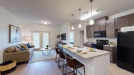 This single-floor residence offers a thoughtfully designed open-concept layout that seamlessly connects the kitchen, dining, and living areas. The kitchen is a standout feature, equipped with rich dark-toned cabinetry, black appliances including a gas range, built-in microwave, and refrigerator, complemented by granite countertops and a large central island with bar seating for three. Stylish pendant lighting illuminates the island, while light wood-style flooring flows throughout the main living areas, adding warmth and continuity.

The living room is bright and inviting, benefiting from natural light that streams in through French doors leading to the outdoors. The space features clean white walls and a comfortable, open feel.

The two bedrooms are carpeted and well-sized, each offering generous walk-in closet space. Large windows in the bedrooms allow for ample natural light and views of the surrounding greenery. Both bathrooms are finished with dark wood vanities, light countertops, wood-style flooring, and shower-tub combinations. Grab bars are present in both bathrooms, reflecting an accessible design.

A dedicated in-unit laundry area with a full-size washer and dryer adds everyday convenience. The overall ambiance is clean, modern, and functional, making this a practical and comfortable single-level home.