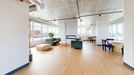 Located atop 1819 Avenue Dollard in Montréal, this rooftop lounge and terrace seamlessly blends indoor comfort with open-air living. The interior lounge is characterized by exposed concrete ceilings, warm light wood flooring, and floor-to-ceiling windows that frame sweeping city views on multiple sides. The industrial-chic aesthetic is softened by stylish furnishings, including plush green sofas, a linear fireplace, and a dedicated dining area with a round table and upholstered chairs. A raised platform area near the large sliding glass doors provides a transitional zone between indoors and the terrace. The outdoor terrace is generously proportioned, finished with large-format porcelain pavers, and anchored by a sleek steel pergola strung with Edison bulb lighting — ideal for evening gatherings. Wicker lounge seating, concrete accent ottomans, and a dining set are arranged throughout the space. A full-size gas BBQ station adds practical entertaining functionality. Perimeter railings open up to panoramic views of the surrounding Montréal cityscape and sky. The combination of refined indoor amenities and a well-equipped outdoor terrace makes this rooftop an exceptional communal destination.