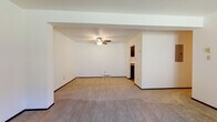 Located at 4563 S Whitnall Ave in St. Francis, Wisconsin, this single-floor unit offers a thoughtfully arranged layout with clearly defined living, sleeping, and functional spaces. The living area is generously proportioned, featuring neutral carpet flooring, crisp white walls, a ceiling fan, and a baseboard heating unit. Structural beam detailing along the ceiling adds subtle architectural character, while an open passage leads directly into the kitchen, promoting a connected flow between spaces.

The galley-style kitchen is well-appointed with dark espresso cabinetry lining both walls, dark granite-style countertops, wood-look flooring, and black appliances including a range with oven and a full-size refrigerator. An overhead exhaust fan and ample upper and lower cabinet storage make this a highly functional cooking space.

The bedrooms are carpeted and feature louvered bi-fold closet doors, white walls, and baseboard heating. One bedroom includes a window with an exterior view, allowing natural light to fill the room. A wall-unit air conditioner is present in one of the rooms for additional climate control.

The bathroom features earthy stone-look tile flooring, tiled tub surround, a toilet, and a dark vanity with granite-style countertop, creating a cohesive and practical finish throughout.
