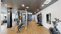Located at 927 W Morgan St in Raleigh, NC, this well-appointed fitness center offers a comprehensive exercise facility across a single open floor. The space is designed with a modern industrial aesthetic, featuring light hardwood-style flooring that contrasts sharply with the dark-painted ceiling, which showcases exposed ductwork and recessed lighting throughout.

The fitness center is equipped with an extensive array of workout equipment to support diverse training needs. Strength training is well covered with a multi-function cable machine system, a Smith machine with an adjustable bench, a dedicated dumbbell rack with a full set of weights, kettlebell storage, and resistance bands. A Matrix-branded cable station is also present, along with additional weight benches and functional training accessories including medicine balls and stability balls.

For cardiovascular training, the space includes treadmills, elliptical machines, and air resistance bikes. Large wall-mounted mirrors are positioned throughout to allow users to monitor their form during workouts.

Natural light filters in through a bank of large windows along one wall, offering views of an adjacent outdoor pool area and the surrounding Raleigh streetscape. Structural columns with a charcoal finish are integrated into the layout, reinforcing the space's modern industrial character. The overall ambiance is clean, functional, and energizing — a well-rounded facility suited for a full-body fitness regimen.