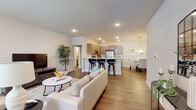 This single-floor residence is thoughtfully designed with an open-concept layout that seamlessly connects the living, dining, and kitchen areas. Wood-look flooring flows throughout the space, contributing to a warm and cohesive aesthetic. The living room is well-lit with recessed lighting and features windows with transom accents near the entry, allowing natural light to fill the space.

The kitchen is equipped with stainless steel appliances, including a refrigerator, range, and microwave, complemented by taupe shaker-style cabinetry and light countertops. A peninsula with bar seating provides additional functionality and connects the kitchen to the main living area. Adjacent to the kitchen, the dining area is illuminated by a brushed nickel chandelier and offers comfortable space for a full dining set.

The bedroom is a calm, neutral retreat with ample room for a workspace, enhanced by a walk-in closet outfitted with wire shelving systems. The bathroom features a tub-shower combination, wood-look flooring, and a vanity with matching cabinetry. A dedicated laundry room includes a full-size front-loading washer and dryer, adding everyday convenience to this well-appointed space.