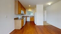 Located at 1600 W Creek Village Dr in Elkton, Maryland, this single-floor residence offers a well-organized layout designed for comfortable everyday living. The kitchen is a functional highlight, featuring warm honey-toned wood cabinetry, dark granite-style countertops, hardwood flooring, and a full suite of white appliances including an electric range, built-in microwave, dishwasher, and refrigerator. A pass-through window connects the kitchen to the living area, enhancing the open feel between the two spaces. The living room is generously sized, finished with neutral carpet and a fireplace, and opens directly to an outdoor area through sliding glass doors that invite natural light. The bedrooms are carpeted and bright, each equipped with ceiling fans and light fixtures; one bedroom features a window with views of surrounding greenery. Two full bathrooms serve the unit, both featuring tub-shower combinations, tile flooring, and wood-toned vanities. Throughout the space, clean white walls and consistent finishes create a cohesive, move-in-ready atmosphere. The layout, as seen in the overhead model view, flows efficiently from the kitchen and living areas through to the private bedroom and bathroom spaces.