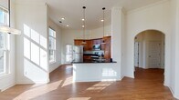 Located at 1194 Blue Ridge Ave in Crozet, VA, this single-floor residence offers a well-designed layout that balances open communal areas with functional private spaces. The heart of the home is an open-concept kitchen and living area distinguished by soaring ceilings, crown molding, and abundant natural light streaming through large windows. The kitchen is outfitted with warm-toned wood cabinetry, dark granite countertops, and a full suite of stainless steel appliances, including a range, microwave, and refrigerator. A peninsula with pendant lighting above serves as a natural divider between the kitchen and the expansive living area, which features hardwood-style flooring and an elegant arched doorway leading to additional rooms. A ceiling fan adds both style and practicality to the bright living space. The bedrooms are carpeted and receive generous natural light, with one room offering views of an outdoor balcony railing. The bathrooms include wood-toned vanities with stone-style countertops, tub-shower combinations, and hardwood-style flooring. Storage is a notable feature, with multiple walk-in closets equipped with wire shelving systems providing ample organization options throughout the unit.