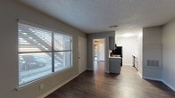 This single-floor unit offers a clean and functional layout designed for comfortable everyday living. The main living area is bright and open, benefiting from a large window fitted with horizontal blinds that allow natural light to fill the space. Dark hardwood-style flooring runs consistently throughout, providing a warm contrast to the soft gray walls and white trim that define the interior palette.

The kitchen is efficiently arranged and features gray cabinetry, a white countertop, and black appliances including a refrigerator and range. It connects seamlessly to the living and dining areas, supporting an open flow through the unit. A textured popcorn ceiling is present throughout, adding a layer of classic residential character.

The bedroom is a comfortable, well-proportioned room equipped with a ceiling fan with a light fixture, providing both airflow and ambient lighting. A floor-to-ceiling mirrored sliding closet offers generous storage while visually expanding the space.

The bathroom is thoughtfully appointed with a gray vanity, white countertop, a large mirror, and contemporary hardware. The separate water closet area includes a full bathtub and shower combination, along with an additional closet or storage nook, keeping the layout organized and practical. The consistent use of hardwood-style flooring throughout ties the entire unit together with a cohesive, modern aesthetic.