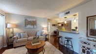This single-floor residence offers a cohesive and functional layout designed for comfortable everyday living. The open-concept living area is anchored by rich dark hardwood flooring, soft neutral wall tones, and a textured ceiling, creating a warm and inviting atmosphere. Large windows and a sliding glass door flood the space with natural light, while vertical blinds and sheer curtains provide privacy. The living room comfortably accommodates a seating area and flows naturally into the dining space, which features a dedicated pendant light fixture and connects seamlessly to the kitchen pass-through bar — complete with granite-style countertops and bar seating.

The galley-style kitchen is efficiently designed with ample white cabinetry, granite-style countertops, stainless steel appliances including a refrigerator, electric range, microwave, and dishwasher, and a practical bi-fold pantry door.

The bedroom offers plush carpeting, generous closet storage, and a calm, neutral palette that promotes rest. Adjacent, the full bathroom features an extended vanity with granite-style countertops, white cabinetry, a full-width mirror, and a shower-tub combination. Throughout the residence, consistent finishes and thoughtful detailing contribute to a cohesive and comfortable living environment.
