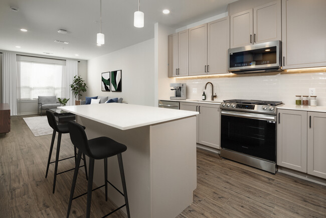 Coming Soon - New West Phase apartments - Finish Package III Kitchen with stainless steel appliances, white quartz countertops, grey cabinetry, pendant lighting, and hard surface flooring (Representative photo) - Avalon Hunt Valley and Hunt Valley West