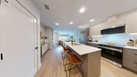 Located at 1946 Ambrosi Rd in Kelowna, BC, this modern two-storey home offers a thoughtfully designed layout spread across two well-proportioned floors. The main level features an open-concept living, dining, and kitchen area finished with warm light wood flooring and recessed lighting throughout. The kitchen is a standout, boasting two-tone cabinetry in taupe and warm wood tones, a white subway tile backsplash, stainless steel appliances, and a generous waterfall island with bar seating — ideal for both cooking and entertaining. The dining area comfortably accommodates a full table and flows seamlessly into the living room, which is anchored by a welcoming entryway with a modern front door featuring sidelights. A convenient half bathroom is also found on this level. Upstairs, two well-appointed bedrooms offer a calm retreat, each finished with the same light wood flooring and neutral tones. The primary bedroom provides a comfortable, serene space, while two full bathrooms serve the upper floor — one featuring large-format grey tile, a soaker tub, and wood-toned vanity cabinetry. Additional built-in open shelving provides practical storage. Clean lines, a neutral palette, and consistent modern finishes give this home a cohesive, contemporary feel throughout.