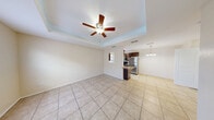 This single-story, 1-bedroom, 1-bathroom home offers a compact yet efficiently designed layout across one level. Light-toned large-format tile flooring flows consistently throughout the space, contributing to a cohesive and easy-to-maintain interior.

The kitchen is a standout feature, outfitted with rich dark-wood cabinetry, granite countertops, and a full suite of stainless steel appliances including a gas range and full-size refrigerator. A peninsula with a built-in sink and breakfast bar provides additional prep space and casual seating, while a pendant chandelier adds a decorative touch over the adjacent dining area. A window allows natural light to brighten the space.

The bedroom is generously proportioned, featuring a tray ceiling with a ceiling fan, a natural light-providing window, and two closets offering ample storage. The room's elevated ceiling detail adds architectural interest and a sense of volume.

The bathroom includes a walk-in shower, dark wood vanity cabinetry, and tile flooring that mirrors the rest of the home. A dedicated laundry area houses a full-size water heater and washer hookup, adding practical utility to the home.

Overall, the space presents a clean, neutral palette with warm wood accents, creating a functional and inviting living environment.