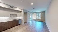 Located at North Grove in Riverside, CA 92501, this well-appointed 1-bedroom, 1-bathroom apartment spans 560 square feet across a single floor. The contemporary building exterior features a clean stucco facade with private balconies and arched entryways, reflecting modern multi-family architectural design.

The kitchen is a standout feature, boasting stainless steel appliances including an LG range, over-the-range microwave, French door refrigerator, and dishwasher. Two-tone cabinetry pairs warm wood-grain lower cabinets with light gray uppers, complemented by a marble-inspired tile backsplash and light quartz countertops. Light hardwood-style flooring runs throughout the main living areas.

The 120-square-foot bedroom features neutral-toned carpet, soft gray walls, and a window offering views of the surrounding community. It connects to a dedicated closet, providing practical storage. The bathroom is finished with a wood-grain vanity, quartz countertop, undermount sink, and a large mirror with overhead lighting. A stacked in-unit washer and dryer is conveniently located within the bathroom area. A hallway connects all rooms, contributing to an efficient and functional layout. The unit presents a clean, modern aesthetic throughout.