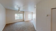 Located at 13700 N Fountain Hills Blvd in Fountain Hills, Arizona, this single-floor unit offers a well-organized and functional layout throughout. The spacious living area is finished with plush carpeting and features multiple windows that invite an abundance of natural light, complemented by a ceiling fan and a textured ceiling overhead. Vertical blinds on a sliding glass door provide access to an outdoor area, extending the living space beyond the interior walls. The kitchen is efficiently designed with ample cream-toned cabinetry offering generous storage, light-colored countertops, tile flooring, and appliances including an electric coil range and an over-the-range microwave. The bedrooms are carpeted and each includes a ceiling fan, with one room featuring direct outdoor access through a sliding glass door fitted with vertical blinds. The bathroom presents a clean, practical design with tile flooring, a vanity with a sink, mirrored cabinet storage, and convenient towel bar fixtures. Throughout the unit, the neutral color palette of warm beige tones creates a cohesive and inviting atmosphere, while the consistent presence of ceiling fans across rooms ensures year-round comfort in the Arizona climate.