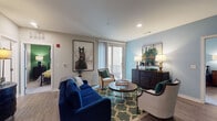 This single-floor residence in Germantown, Tennessee offers a thoughtfully designed layout with two bedrooms and two full bathrooms. The living area is bright and welcoming, featuring wood-style flooring, recessed lighting, and a sliding glass door that provides access to an outdoor balcony and fills the space with natural light. The open connection between the living and dining areas creates a seamless flow throughout the main living space.

The kitchen is well-equipped with gray shaker-style cabinetry extending to the ceiling, white subway tile backsplash, light quartz countertops, and a full suite of stainless steel appliances including a refrigerator, range, microwave, and dishwasher. A dedicated dining area adjacent to the kitchen comfortably accommodates a full dining set.

Each bedroom features plush carpeting, large windows with natural light, and accent walls that add a distinct character to each room. One bedroom features a bold teal accent wall, while the other showcases a rich green tone. Both bathrooms are finished with gray vanity cabinetry, white countertops, and light tile flooring, offering clean, modern aesthetics. The overall design balances contemporary finishes with a warm, livable ambiance throughout.