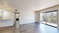 This 1-bedroom, 1-bathroom unit is thoughtfully designed to maximize its floor area across a single level. The open living room is a standout feature, finished with durable wood-style flooring, crisp white walls, and a textured ceiling. A large sliding glass door floods the space with natural light and provides direct access to an outdoor area, offering pleasant views of surrounding greenery.

The kitchen is well-equipped and modern, featuring granite-style countertops, white upper cabinetry, and contrasting gray lower cabinets accented by a classic white subway tile backsplash. Stainless steel appliances — including a refrigerator, dishwasher, range, and microwave — complete the space, making it both functional and visually appealing.

The bedroom is a comfortable retreat, carpeted for warmth and equipped with a ceiling fan and a window that brings in natural light. A dedicated closet provides convenient storage. The bathroom includes a full tub-shower combination with white tile surround and clean, neutral finishes throughout.

A hallway connects the rooms efficiently, and the layout as a whole presents a clean, neutral palette that offers a versatile canvas for personalization.