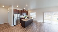 This well-appointed single-floor unit offers a thoughtfully designed open-concept layout that connects the kitchen and living area seamlessly. The kitchen is a standout feature, showcasing rich dark-stained cabinetry that extends to the ceiling, granite countertops, a central island with a built-in sink, and a full suite of stainless steel appliances including a refrigerator, range, and microwave. Recessed lighting illuminates the space, while durable wood-look flooring runs throughout the main living area, adding warmth and easy maintenance.

The living area is bright and airy, benefiting from natural light through a sliding glass door and additional windows, with a wall-mounted HVAC unit providing climate control. Two generously sized bedrooms feature plush wall-to-wall carpeting, baseboard heating, and windows with blinds that allow for adjustable natural light. Both bedrooms offer a calm, neutral palette ideal for comfortable living.

The unit includes two full bathrooms, each finished with granite-topped dark wood vanities, tiled flooring in an earthy stone pattern, and a shower/tub combination. The overall design is clean and contemporary, with neutral tones, white ceilings, and consistent finishes that create a cohesive and inviting atmosphere throughout.
