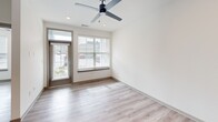 Located at 2311 Odell School Rd in Charlotte, NC, this thoughtfully designed 2-bedroom, 1-bathroom unit offers a clean, modern aesthetic across a single floor. The open-concept kitchen and living area forms the heart of the space, showcasing a large quartz-topped island with an undermount sink, light wood cabinetry, a classic white subway tile backsplash, and a full suite of stainless steel appliances including a refrigerator with ice maker, electric range, and over-the-range microwave. The living area benefits from natural light streaming through large windows and a glass-panel door, complemented by a ceiling fan and recessed lighting overhead. Luxury vinyl plank flooring flows consistently throughout the entire unit, adding warmth and durability. The primary bedroom is a well-proportioned retreat featuring dual windows, a ceiling fan, and access to a dedicated walk-in closet with built-in shelving and hanging rods. The second bedroom also offers bright windows and a ceiling fan. The bathroom is finished with a wood-toned vanity, dark countertop, framed mirror, and overhead wall-mounted cabinetry for added storage. The unit's neutral white walls and cohesive finishes create a bright, move-in-ready environment.