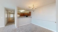 Located at 107 Ashford Dr in West Monroe, Louisiana, this single-story home offers a functional and comfortable layout across a generously sized floor plan. The open living and dining area is finished with plush carpet and neutral gray walls, creating a clean, welcoming atmosphere. A stylish chandelier anchors the dining space, while a peninsula-style kitchen features warm medium-toned wood cabinetry, granite-look countertops, stainless steel appliances including a microwave and refrigerator, and a breakfast bar that opens to the living area — ideal for both everyday use and casual entertaining. A hallway connects the main living area to the private bedroom and additional rooms. The spacious primary bedroom is carpeted and includes a ceiling fan, two closets — one of which is a walk-in — and a standout arched window that fills the room with natural light and outdoor views. The full bathroom includes a soaking tub with full tile surround and built-in shelving. A dedicated laundry room adds practical convenience to the layout. Throughout the home, consistent neutral tones, clean white trim, and carpet flooring contribute to a cohesive and comfortable living environment.