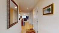 This two-story home offers a thoughtfully designed layout that balances comfort and functionality across both levels. The entryway welcomes visitors with warm tile flooring and recessed lighting, opening into an expansive living area with plush carpeting and an open view to the upper floor's balcony railing above. The living room is anchored by generous seating and flows seamlessly into the dining area and kitchen beyond. The kitchen is well-equipped with rich wood cabinetry extending to the ceiling, granite countertops, black appliances including a gas range, and a central island, all illuminated by recessed lighting. A dedicated dining nook features a pendant chandelier and large windows that invite natural light and outdoor views. A cozy study offers built-in bookshelves and a relaxed seating area, ideal for reading or quiet work. The primary bedroom is distinguished by a tray ceiling with crown molding, a ceiling fan, plush carpeting, and multiple windows. Its en-suite bathroom includes a double-sink vanity with warm wood cabinetry, tile flooring with a diagonal pattern, and a soaking tub. An additional bedroom features carpeting, a ceiling fan, and ample space adaptable for multiple uses. A secondary bathroom provides a clean, functional design with tile flooring and a wood vanity.