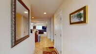 This two-story home offers a thoughtfully designed layout that balances comfort and functionality across both levels. The entryway welcomes visitors with warm tile flooring and recessed lighting, opening into an expansive living area with plush carpeting and an open view to the upper floor's balcony railing above. The living room is anchored by generous seating and flows seamlessly into the dining area and kitchen beyond. The kitchen is well-equipped with rich wood cabinetry extending to the ceiling, granite countertops, black appliances including a gas range, and a central island, all illuminated by recessed lighting. A dedicated dining nook features a pendant chandelier and large windows that invite natural light and outdoor views. A cozy study offers built-in bookshelves and a relaxed seating area, ideal for reading or quiet work. The primary bedroom is distinguished by a tray ceiling with crown molding, a ceiling fan, plush carpeting, and multiple windows. Its en-suite bathroom includes a double-sink vanity with warm wood cabinetry, tile flooring with a diagonal pattern, and a soaking tub. An additional bedroom features carpeting, a ceiling fan, and ample space adaptable for multiple uses. A secondary bathroom provides a clean, functional design with tile flooring and a wood vanity.