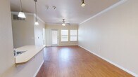 This single-story, 1-bedroom, 1-bathroom residence offers a thoughtfully designed layout that maximizes both function and comfort. The open-concept living, dining, and kitchen area forms the heart of the home, featuring warm wood-look flooring, crisp crown molding, and a ceiling fan that enhances airflow and ambiance. Natural light filters in through multiple windows, brightening the space throughout the day. A private entry door with a sidelight window adds a welcoming touch to the main living area.

The kitchen is equipped with dark cabinetry, a full-size refrigerator, and a countertop that flows into a convenient breakfast bar, seamlessly connecting to the living and dining zones. Pendant lighting accents the kitchen area, adding a polished detail.

The bedroom is carpeted for comfort and offers a well-proportioned footprint with ample wall space. It connects directly to the bathroom, which features an extended vanity with dark cabinetry, a large mirror, and overhead lighting. Adjacent to the bathroom is a spacious walk-in closet outfitted with wire shelving and hanging rods across multiple walls, providing generous storage capacity. A second closet adds further organizational flexibility. The unit also includes a dedicated laundry area, rounding out the practical amenities of this efficiently designed residence.