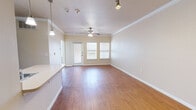 This single-story, 1-bedroom, 1-bathroom residence offers a thoughtfully designed layout that maximizes both function and comfort. The open-concept living, dining, and kitchen area forms the heart of the home, featuring warm wood-look flooring, crisp crown molding, and a ceiling fan that enhances airflow and ambiance. Natural light filters in through multiple windows, brightening the space throughout the day. A private entry door with a sidelight window adds a welcoming touch to the main living area.

The kitchen is equipped with dark cabinetry, a full-size refrigerator, and a countertop that flows into a convenient breakfast bar, seamlessly connecting to the living and dining zones. Pendant lighting accents the kitchen area, adding a polished detail.

The bedroom is carpeted for comfort and offers a well-proportioned footprint with ample wall space. It connects directly to the bathroom, which features an extended vanity with dark cabinetry, a large mirror, and overhead lighting. Adjacent to the bathroom is a spacious walk-in closet outfitted with wire shelving and hanging rods across multiple walls, providing generous storage capacity. A second closet adds further organizational flexibility. The unit also includes a dedicated laundry area, rounding out the practical amenities of this efficiently designed residence.