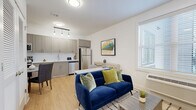 Located at 110 Bergen Tpke in Little Ferry, NJ, this thoughtfully designed one-bedroom, one-bathroom unit offers a compact yet highly functional layout across a single floor. The open-concept living and kitchen area creates a welcoming, airy atmosphere, with warm light wood flooring flowing throughout the space. The kitchen is well-equipped with stainless steel appliances — including a refrigerator, electric range, built-in microwave, and dishwasher — complemented by taupe shaker-style cabinetry, white countertops, and pendant lighting. A cozy dining nook adjacent to the kitchen provides an ideal space for everyday meals. The living area is bright and comfortable, benefiting from natural light through a large window. The bedroom offers a peaceful retreat with light wood flooring, soft neutral walls, and a window that brings in additional natural light. The bathroom is finished with clean white tile, a walk-in glass-enclosed shower with large-format gray tile surround, a single vanity with a white countertop, and light tile flooring — conveying a modern, spa-like simplicity. Overall, the unit presents a clean, contemporary aesthetic that is both practical and inviting.