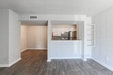 Located at 2159–2165 Godby Rd in College Park, Georgia, this single-floor residence offers a clean, contemporary layout designed for comfortable everyday living. Rich wood-look vinyl flooring runs consistently throughout the unit, providing both durability and a cohesive aesthetic from room to room.

The entry foyer welcomes residents through a solid six-panel door and opens into the main living area, which is bright and open, featuring a large sliding glass door dressed with vertical blinds that allow natural light to fill the space. The open-concept flow connects the living area to the dining space and kitchen via a half-wall pass-through with granite countertop detailing.

The galley-style kitchen is well-appointed with white cabinetry featuring sleek bar-pull hardware, granite countertops, and a full suite of stainless steel appliances including an electric range, refrigerator, and dishwasher. A ventilation hood above the range and ample cabinetry provide practical storage and functionality.

The bedroom is generously sized with a window offering natural light, neutral gray walls, and closet access. An additional room provides flexible space suitable for a second bedroom or office. The bathroom features a granite-topped white vanity with an undermount sink, a full tub/shower combo, and wood-look flooring that ties into the rest of the unit's design. Central HVAC ensures year-round comfort throughout the home.