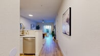 This well-appointed single-floor residence offers five bedrooms and three full bathrooms, thoughtfully designed to maximize functionality and comfort. The open-concept kitchen and living area serves as the heart of the home, featuring white shaker-style cabinetry with gold hardware, quartz countertops, a marble-look tile backsplash, and stainless steel appliances including a range with over-the-range microwave and dishwasher. Light wood-look flooring runs consistently throughout the unit, creating a cohesive and modern aesthetic. The living area is bright and airy, equipped with a ceiling fan and recessed lighting, and opens toward a window that fills the space with natural light. The bedrooms are clean and neutral in tone, each featuring light wood flooring, blinds, and ceiling fans for comfort. The primary bathroom offers a dual-sink vanity with white cabinetry and well-lit mirrors, while secondary bathrooms include a tub-shower combination. Four closets provide generous storage throughout the unit. Two hallways connect the various rooms efficiently, contributing to a smart and functional floor plan. Overall, the space presents a fresh, contemporary feel with clean lines, neutral finishes, and practical design throughout.