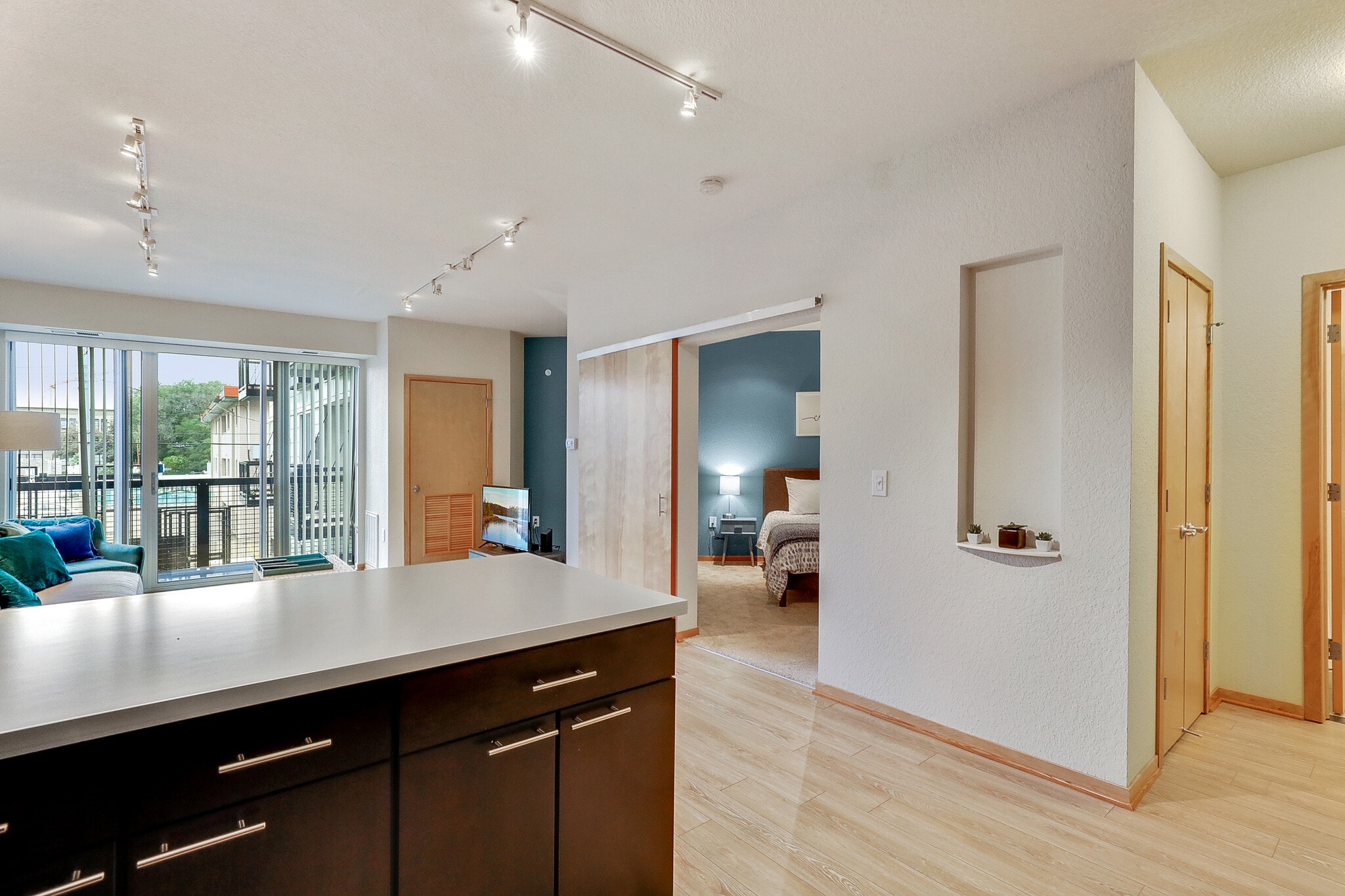 Modern kitchen island with dark cabinets and a view of the living room and bedroom.
