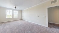 Located in Bradenton, FL, this well-appointed 2-bedroom, 2-bathroom residence offers a thoughtfully designed single-floor layout. The kitchen serves as a central highlight, featuring dark espresso cabinetry, light quartz countertops, stainless steel appliances including a refrigerator, range, microwave, and dishwasher, and a peninsula with pendant lighting and crown molding accents. Light wood-style flooring runs through the kitchen and living areas, complementing the neutral warm-toned walls. A convenient in-unit laundry closet with full-size washer and dryer is accessible directly from the kitchen. The spacious living area includes a ceiling fan, crown molding, a textured ceiling, and windows that invite natural light and outdoor views. Both bedrooms are carpeted and offer a comfortable sense of space, each with a window providing natural light. The generously sized primary bedroom includes direct access to its own bathroom. Both bathrooms are finished with dark espresso vanities, light countertops, large mirrors, and wood-style tile flooring. One bathroom features a tub/shower combination, while the other includes a shower with curtain. Two dedicated closets provide ample storage throughout the residence.