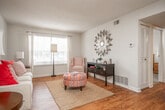 This single-floor, 2-bedroom, 2-bathroom residence offers a practical and well-organized layout. The living room is bright and welcoming, featuring warm hardwood-style flooring, neutral walls, and windows that allow natural light to fill the space. The open flow between the living and dining areas creates a cohesive entertaining space, with the dining area accommodating a ceiling fan overhead and a pass-through window connecting to the kitchen.

The galley-style kitchen runs along a compact corridor, featuring white cabinetry, white appliances, and continuous hardwood-style flooring, providing efficient use of space. A louvered closet door within the kitchen area offers additional storage access.

Both bedrooms are carpeted and include closets—the primary bedroom features a walk-in closet, while the second bedroom is equipped with a sliding-door double closet. Each room is adequately sized to comfortably accommodate standard bedroom furnishings.

The two bathrooms mirror each other in style, with white vanities, hardwood-style flooring, and clean, functional fixtures. One bathroom includes a full tub-shower combination, while the second serves as a half bath. A hallway connects the main living areas to the bedrooms and bathrooms, completing this efficient and cohesive floor plan.