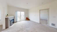 Located at 436 Broadway in downtown Tacoma, WA, this single-floor, three-bedroom, one-bathroom unit offers a well-organized layout across a compact but efficiently designed footprint. The living room serves as a welcoming central space, featuring plush carpeting, a fireplace, and sliding glass doors that open to a balcony with views of the surrounding cityscape, allowing natural light to fill the room. The kitchen is thoughtfully appointed with light wood cabinetry, stainless steel appliances including a refrigerator, microwave, and range, complemented by white countertops, a stainless steel sink, warm hardwood-style flooring, and pendant and track lighting overhead. The three bedrooms are carpeted and finished with clean white walls; the primary bedroom offers a generous footprint with a window framing outdoor views, while another bedroom includes a sliding-door closet with built-in rod storage. The bathroom features a modern vessel sink atop a light wood vanity with white countertop, a tub-shower combination, and bright vanity lighting. A stacked washer and dryer unit is conveniently accessible within the bathroom area. The overall aesthetic is clean, contemporary, and move-in ready.