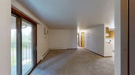 Located at 2503 Jenny Ln in Green Bay, Wisconsin, this single-floor, two-bedroom, one-bathroom home offers a practical and comfortable layout. The living room is generously sized, finished with neutral carpeting, baseboard heating, and a sliding glass door that opens to an outdoor patio, bringing in natural light and views of the surrounding greenery. Adjacent to the living area, the dining space features warm wood-look flooring and a stylish multi-light pendant chandelier overhead. The kitchen is efficiently designed in a U-shape configuration, offering ample oak cabinetry, light-toned countertops, a double-basin sink, and white appliances including a range and full-size refrigerator, all set on light hardwood-style flooring. The primary bedroom is a comfortable size, highlighted by dual bi-fold closets with warm wood-toned doors and a window that lets in natural light. The second bedroom also features carpeting, a baseboard heater, and a full closet. A walk-in closet with built-in shelving and hanging rods provides excellent storage. The full bathroom is well-appointed with a wood-front vanity, light countertop, a tub-shower combination, and light wood-look flooring, completing this tidy and functional home.