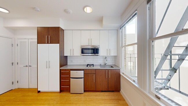 Kitchen with wood flooring, cabinets, built-in appliances, and large windows - 540 Leavenworth Street