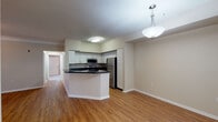 This single-floor residence offers a thoughtfully designed open-concept layout that connects the kitchen and living areas seamlessly. The kitchen is equipped with stainless steel appliances, including a refrigerator, range, and microwave, all complemented by white cabinetry and dark granite-style countertops. A peninsula with a raised breakfast bar adds functional workspace and informal dining space. Wood-style flooring runs throughout the kitchen and living areas, creating a cohesive, warm aesthetic.

The living room is generously sized, featuring crown molding, a ceiling fan, and a sliding glass door that admits natural light and provides outdoor access. The bedrooms are carpeted for comfort, each with ceiling fans and ample natural light from windows with blinds. The primary bedroom connects directly to a private bathroom and offers convenient hallway access.

Both bathrooms are finished consistently, featuring white cabinetry, dark granite-style countertops, single-basin sinks, tiled tub-shower combinations, and wood-style flooring. A multi-bulb vanity light fixture provides bright, even illumination in each bathroom. Neutral wall tones throughout the unit create a clean, versatile backdrop suitable for a variety of interior styles.