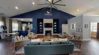 The Waterford clubhouse at 704 Shell Dr in Spring Lake, NC is a thoughtfully designed single-story community facility that blends modern aesthetics with functional amenities. Upon entry, a soaring vaulted reception area greets visitors with warm wood-look flooring, a reception desk, and an open sightline into the main lounge and dining spaces.

The centerpiece lounge commands attention with its dramatic vaulted ceiling, bold navy accent wall bearing the Waterford name and logo, and a tile-surround fireplace flanked by decorative geometric shelving. A large ceiling fan and plush seating arrangements create a welcoming, residential atmosphere. Adjacent to the lounge, a dining nook features a deep navy accent wall, contemporary pendant lighting, and natural light from nearby windows.

The well-appointed kitchen area incorporates navy and cream cabinetry, dark granite countertops, stainless steel appliances, and rich wood-look flooring. A dedicated business center provides built-in navy cabinetry, dark countertops, and computer workstations beneath a teal accent wall.

The expansive fitness center is equipped with strength machines, free weights, cardio equipment, resistance bands, stability balls, and a BOSU trainer. A separate media room features deep navy walls, a large wall-mounted TV, surround sound speakers, and a curated library of DVDs.