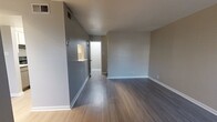 This two-story, one-bedroom, one-bathroom residence offers a thoughtfully laid-out floor plan across two levels. The main floor features a welcoming living room with soaring ceilings, a tile-surround fireplace, and hardwood-style flooring that extends throughout the space, creating a warm and cohesive aesthetic. Natural light filters in through slatted blinds, enhancing the open ambiance. A pass-through connects to the galley-style kitchen, which is equipped with black appliances including a refrigerator, range, and dishwasher, complemented by white cabinetry, light countertops, and additional natural light from a window at the far end. The adjacent dining area provides a seamless flow between cooking and entertaining spaces. A dedicated laundry area on the main level accommodates a full-size side-by-side washer and dryer. Upstairs, the spacious primary bedroom features plush carpet, a ceiling fan with light fixture, and a window for natural light. It connects directly to a generously sized bathroom with an L-shaped dual-vanity, stone-look countertops, and well-lit mirrors. Two closets, including a large walk-in with multi-tier shelving and hanging rods, provide ample storage throughout the home.